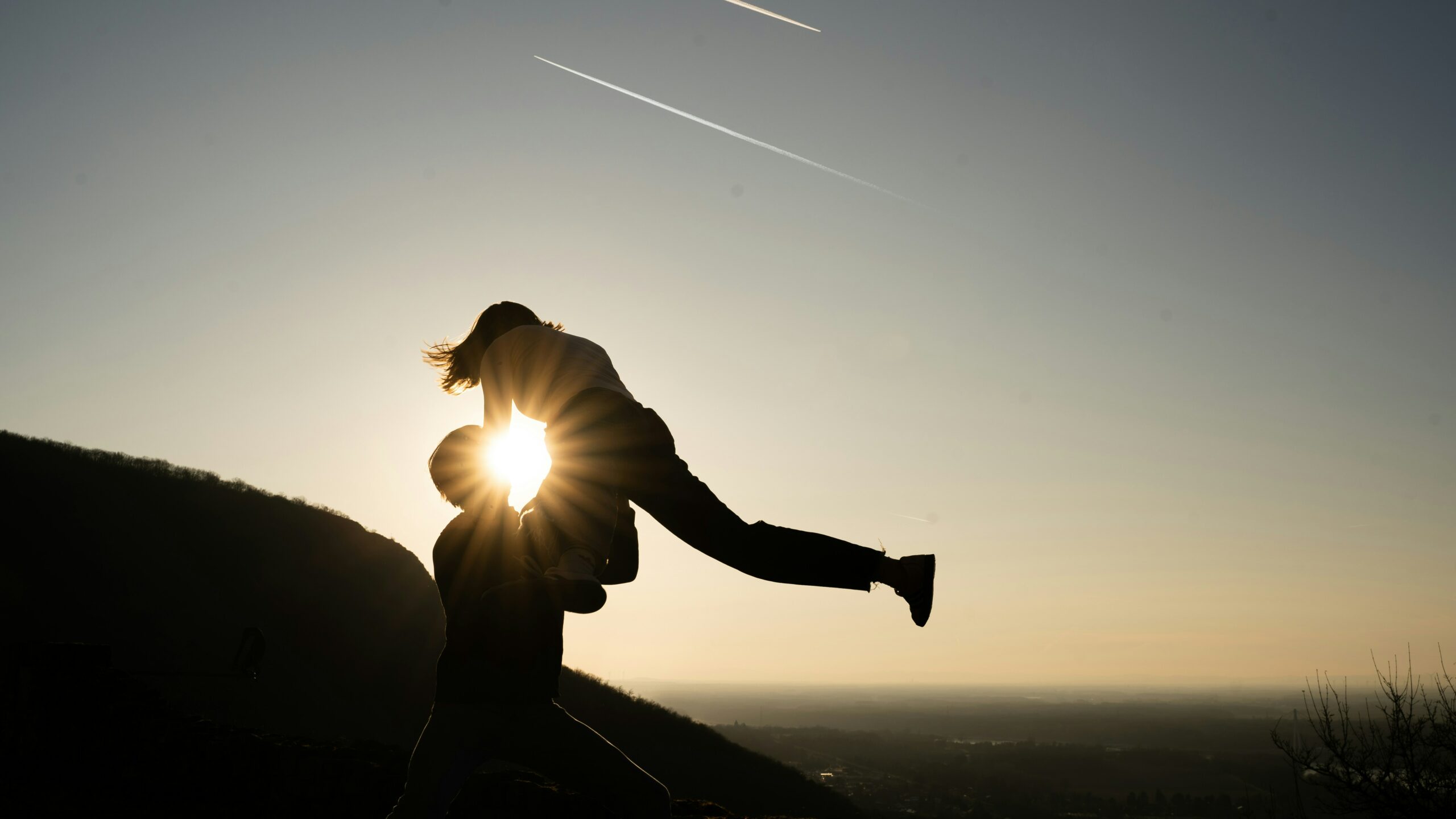 Couple s’amusant au soleil levant, l’homme fait voltiger sa partenaire et le soleil danse avec eux.